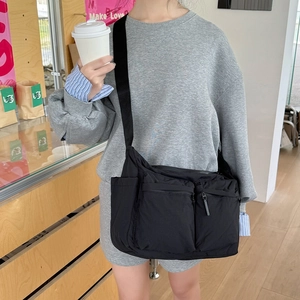 Détail d'un sac bandoulière en nylon noir avec plusieurs poches et un style utilitaire