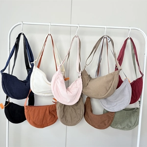 Detailed row of solid color corduroy crescent bags in various colors hanging on a rack
