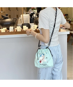 Detail of mint green drawstring crossbody bag with plush cartoon embroidery and rope strap