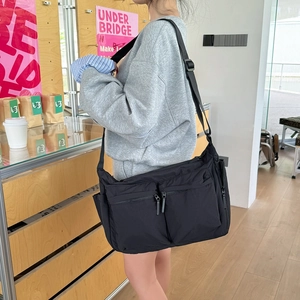 Détail du sac bandoulière en nylon noir durable avec de multiples poches et sangle réglable