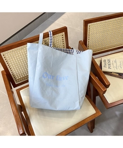 Detail of light blue tote bag with check lining and art font on a vintage chair