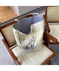 Close-up of cute puppy embroidery and blue checkered lining on beige tote bag