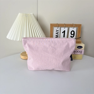 Détail d'une trousse de maquillage en nylon rose avec fermeture éclair et texture froissée