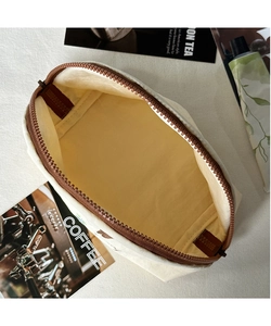 Dettaglio della borsa da toilette beige che mostra l'interno spazioso e la cerniera