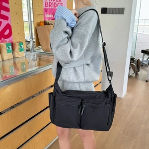 Détail du sac bandoulière en nylon noir avec plusieurs poches et une sangle réglable