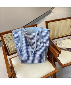 Blue and white checkered tote bag with woven texture placed on a rustic wooden chair