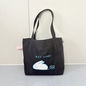Detail of cute white rabbit embroidery and May Rabbit text on black nylon tote bag