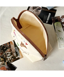 Dettaglio del beauty case con ricamo a orsetto, cerniera e interno giallo brillante