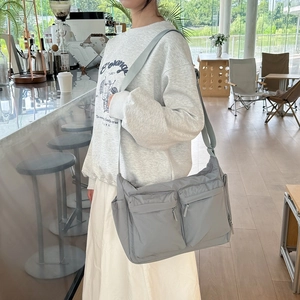 Détails du sac bandoulière gris en nylon avec doubles poches zippées et large sangle réglable