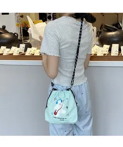 Detail of mint green drawstring crossbody bag featuring a cute cartoon bear and music print