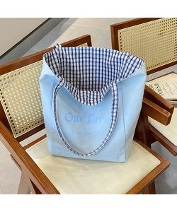 Close-up of light blue canvas tote bag with blue and white checkered lining on a chair