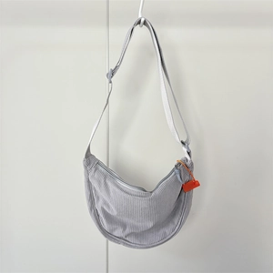 Close-up of light grey corduroy dumpling bag texture with adjustable strap on white hook