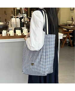 Detail of blue and white checkered cotton tote bag with vintage metal oval logo plaque