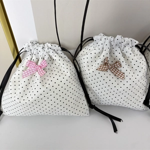 Close-up of polka dot drawstring pouches with decorative plaid bows for jewelry storage