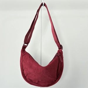 Detailed texture of burgundy corduroy crescent bag with adjustable strap and zipper