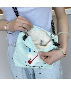 Macro view of light green canvas bag showing puppy embroidery and zip pocket interior