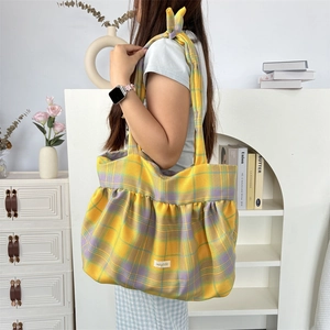 Gros plan d'un grand sac cabas en toile à carreaux jaunes avec détails plissés et bandoulière
