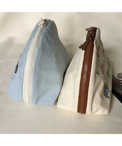 Dettaglio di trousse ricamate con cerniera marrone e cursore a forma di testa di orso