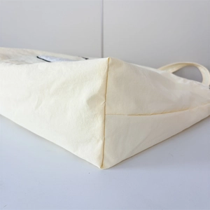 Close-up of the reinforced corner stitching on a beige nylon tote bag with precise seams