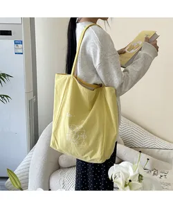 Vue latérale d'un sac cabas en toile jaune avec imprimé porté par un mannequin