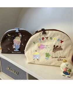 Dettaglio di trousse in tela ricamata con motivi a cartoni animati su uno scaffale