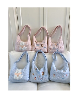 Detail of quilted cotton tote bags with cartoon embroidery in pink and light blue colors