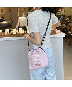 Detail of pink canvas drawstring bag featuring cartoon embroidery and woven strap