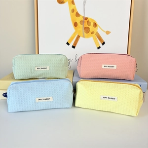 Close-up of colorful waffle knit pencil cases in pastel pink, blue, green and yellow