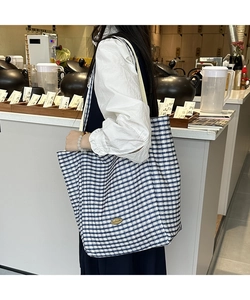 Detail view of blue and white checkered canvas tote bag with handmade label and sturdy handle