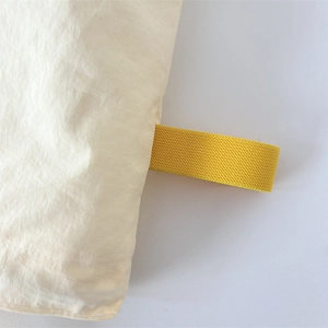 Close-up of industrial sewing on a beige fabric bag with high-density yellow elastic band