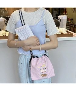 Detail of light pink canvas drawstring bag featuring colorful animal embroidery patterns