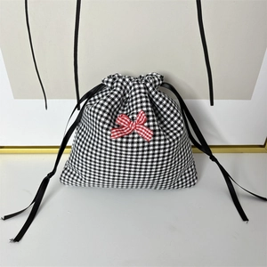 Close-up of houndstooth fabric drawstring pouch with a decorative red checkered bow