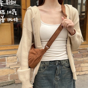 Close-up of brown corduroy crossbody bag paired with beige knitted cardigan and denim skirt