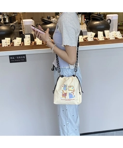 Detail of a beige canvas drawstring bag with cat print and woven adjustable strap