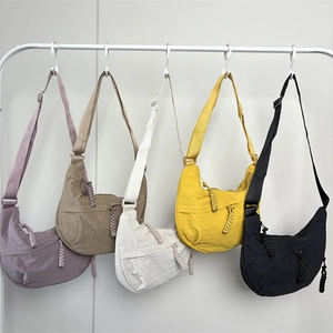 Detail of colorful nylon dumpling bags with pleated texture and braided zip pullers