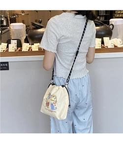 Detail of canvas shoulder bag featuring colorful cat embroidery and woven strap