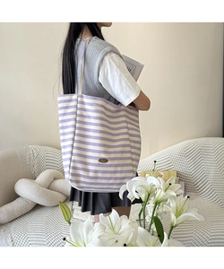 Détail du sac cabas en toile à rayures mauves avec texture et étiquette de marque