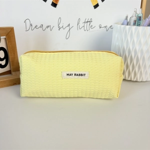 Detail of yellow waffle texture pencil case with branded woven label on the surface