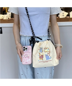 Detail of canvas drawstring bucket bag featuring colorful cat embroidery and plaid strap