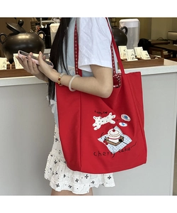 Detail of red canvas tote bag featuring cute dog illustration and red checkered straps
