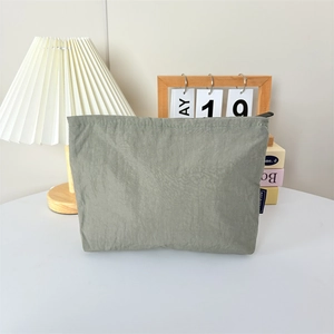 Détail macro d'une trousse de maquillage en nylon vert sauge avec étiquette tissée