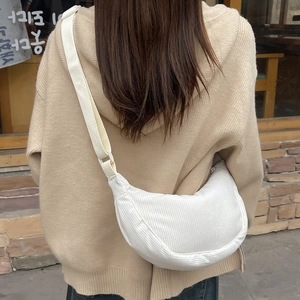 Detailed macro view of white corduroy crescent bag showing fabric texture and adjustable strap