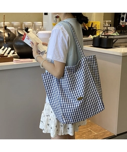 Close-up of blue and white checkered canvas tote bag with a metal logo tag and large capacity