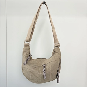 Detail of beige nylon dumpling bag featuring unique long woven zipper pullers on wall