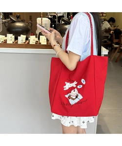 Detail of red canvas tote bag with cute cartoon dog illustration and cherry cake print