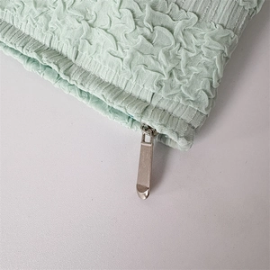 Close-up of mint green pleated texture fabric with high-quality silver metal zipper detail
