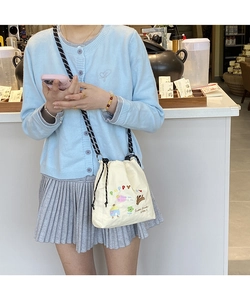 Detail of off-white canvas bucket bag featuring cute puppy embroidery and striped strap