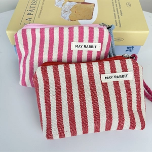 Detail of striped canvas coin purses in pink and red with May Rabbit label