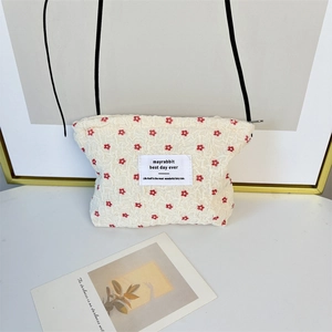 Detail of floral seersucker cosmetic bag with red flowers and white woven brand label