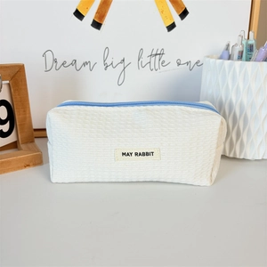 Close-up of white waffle texture pencil case with blue zipper and May Rabbit fabric label